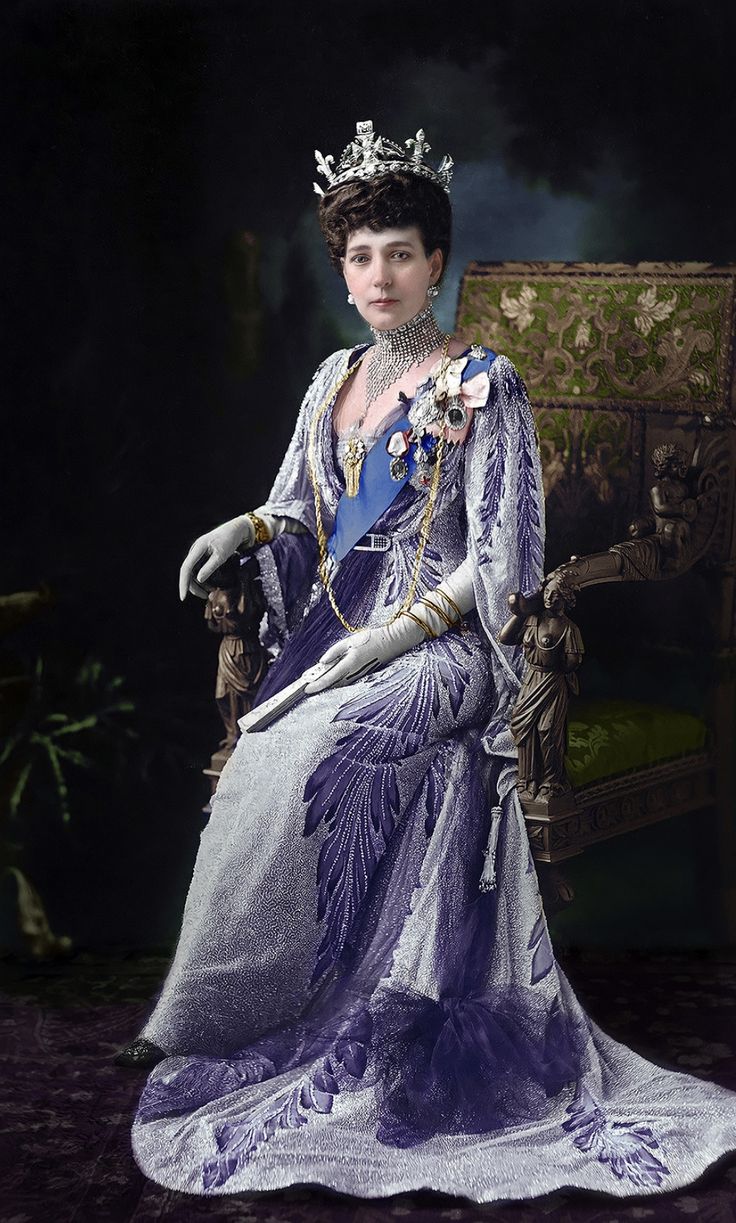 a woman in a purple dress and tiara sitting on a chair wearing a crown