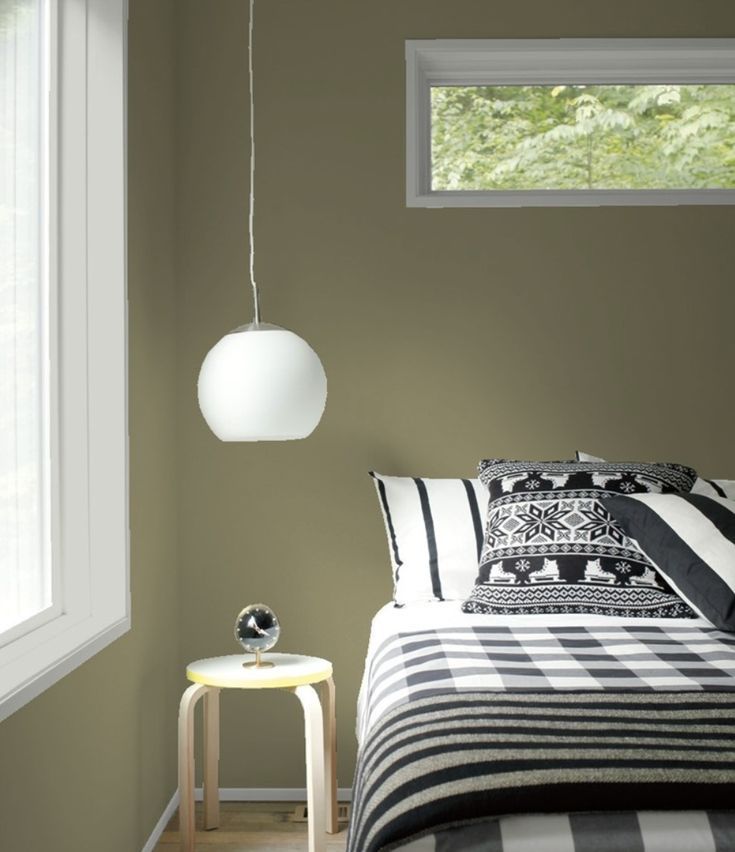 a bed room with a neatly made bed and a lamp hanging from the ceiling above it