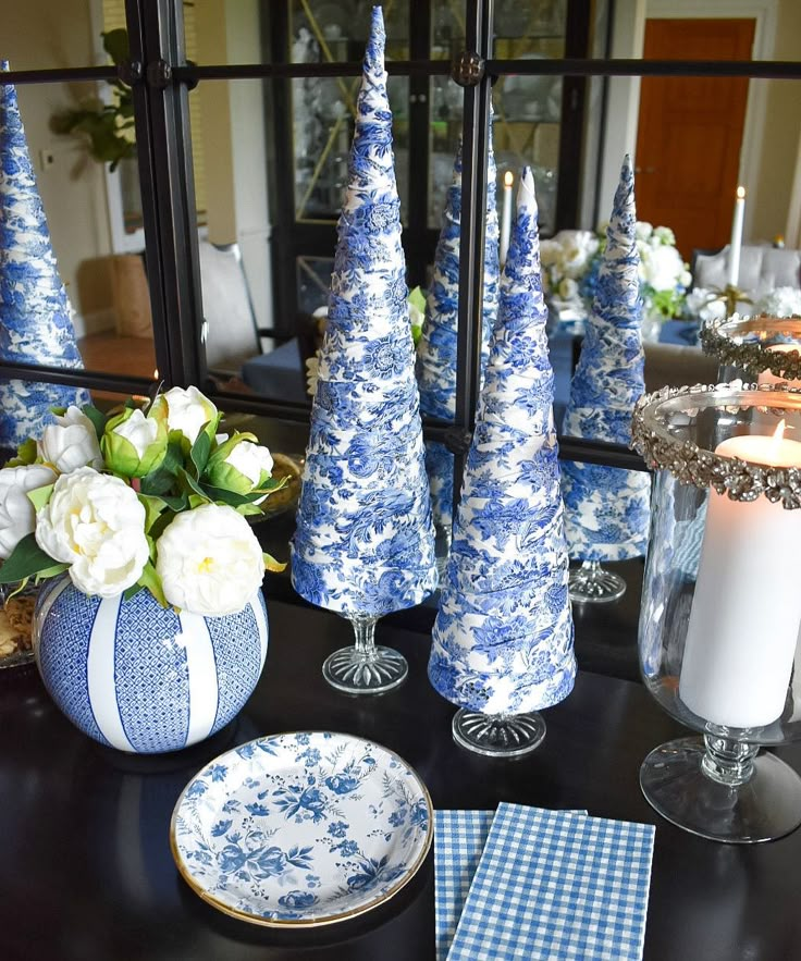 blue and white christmas decorations on a dining room table with candles, plates and napkins