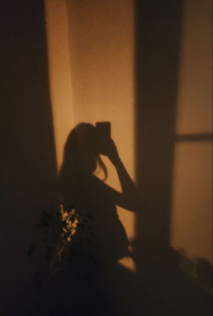 the shadow of a woman's head is cast on a wall by a window