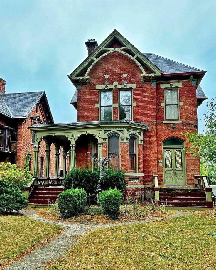 an old red brick house sitting on top of a lush green field