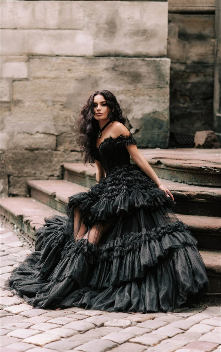 a woman in a black dress standing on some steps