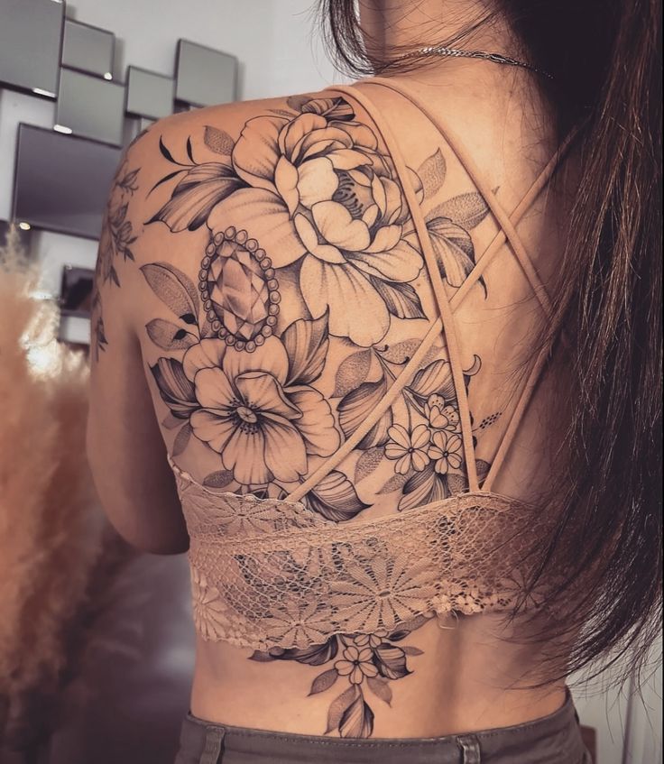 the back of a woman's shoulder with flowers and laces on her arm