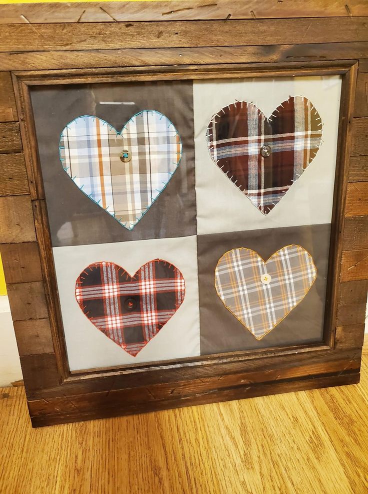 a wooden frame with four different heart shaped patches in the shape of hearts on it