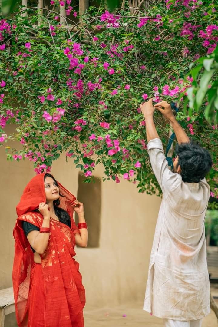 a man taking pictures of a woman under a tree