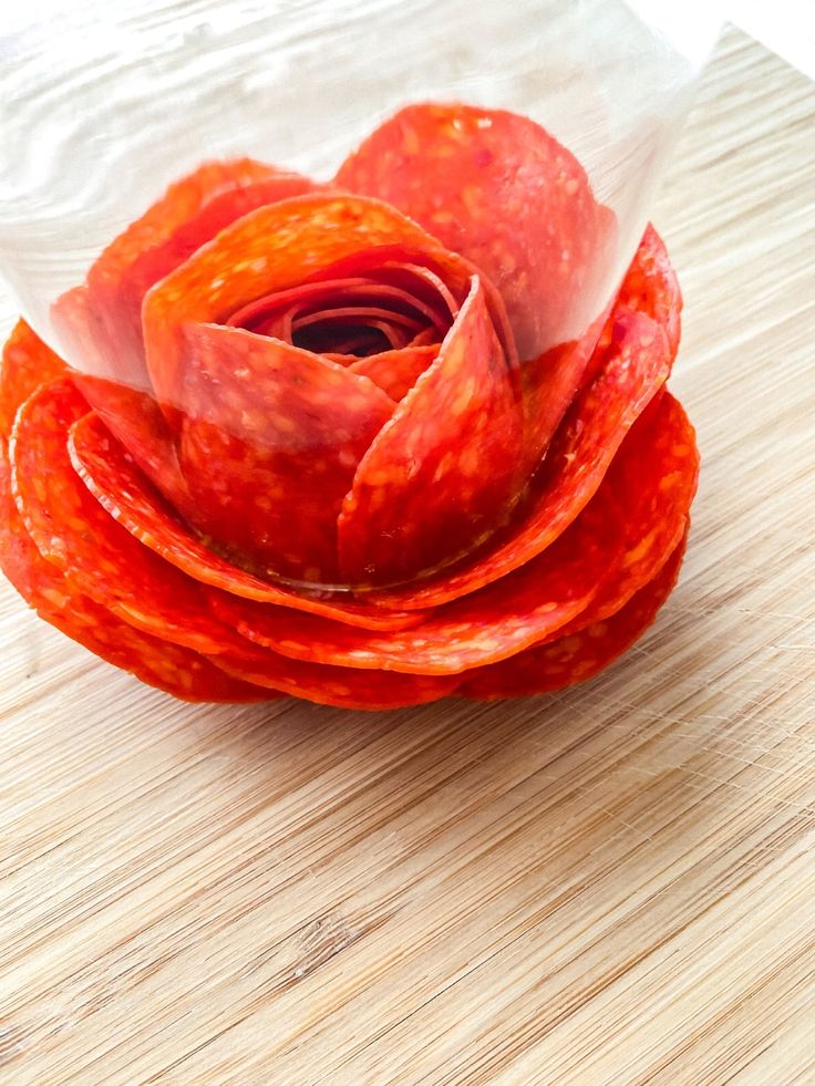 a red flower sitting on top of a wooden table