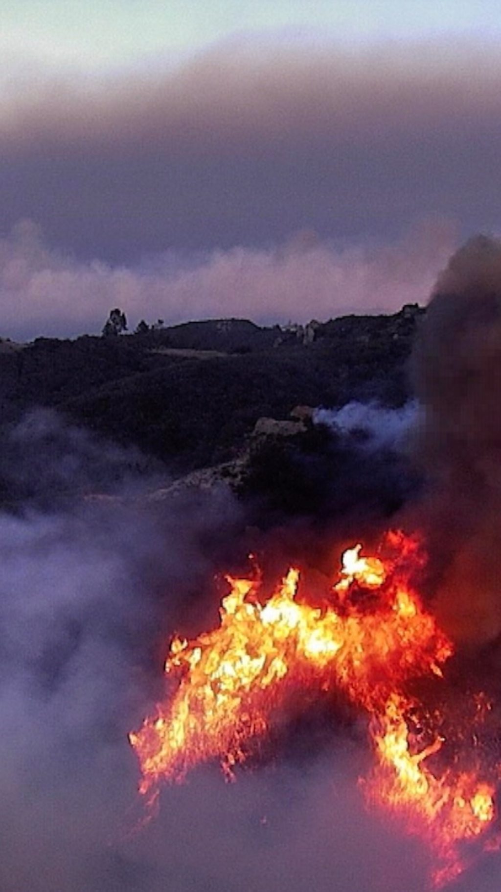 Smoking hills in an evening light, with a large fire in the foreground