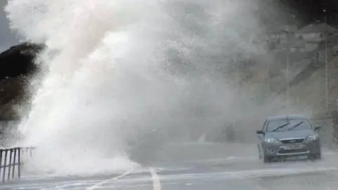 A car is covered by a huge wave on the promenade at Colwyn Bay