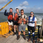 Photo of the students standing posing on the boat.