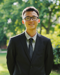 Portrait of Xiang in front of some green trees.