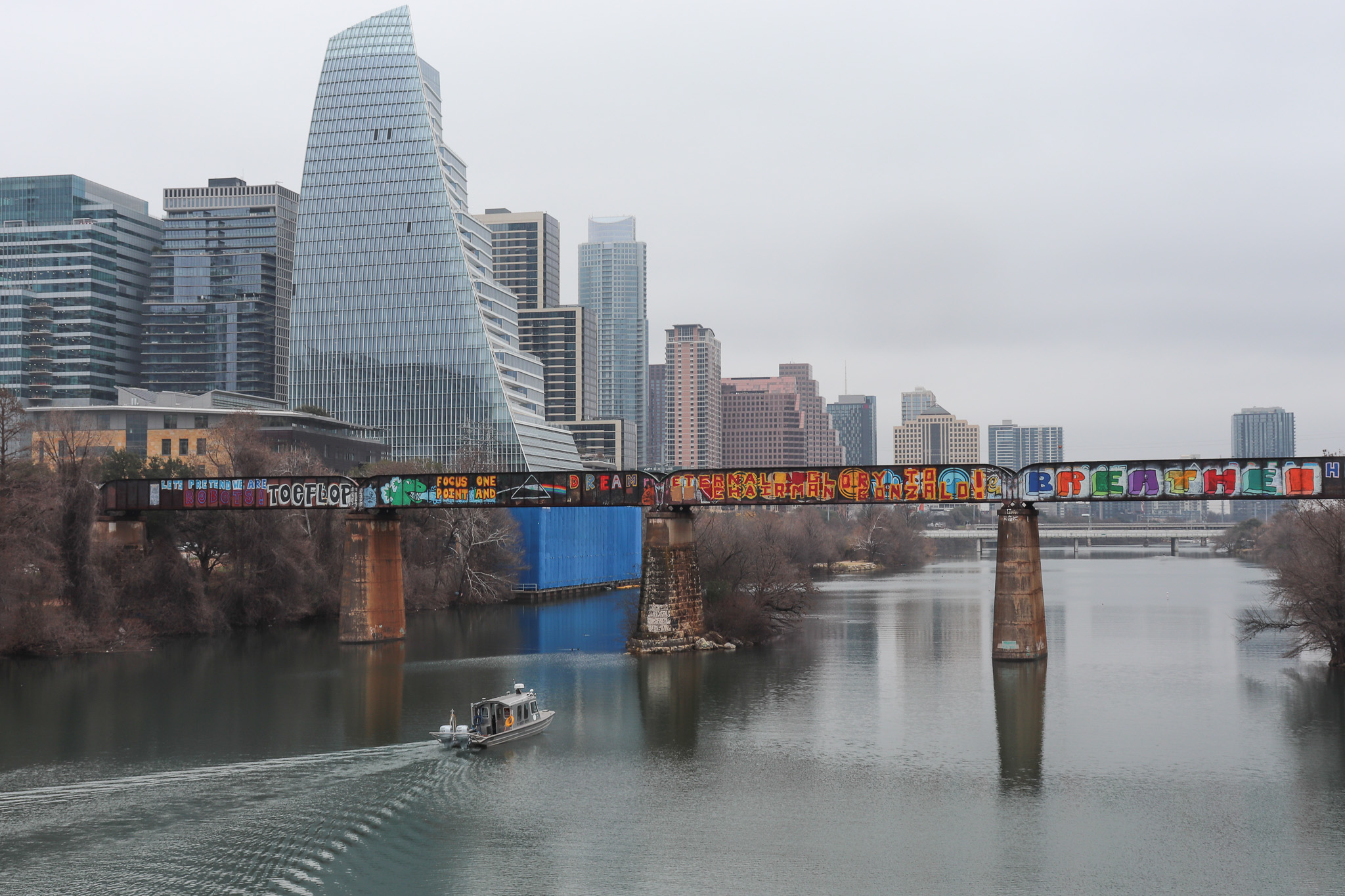 Scene of downtown Austin with the RV Scott Petty sailing east along the lake and passing under the railway bridge