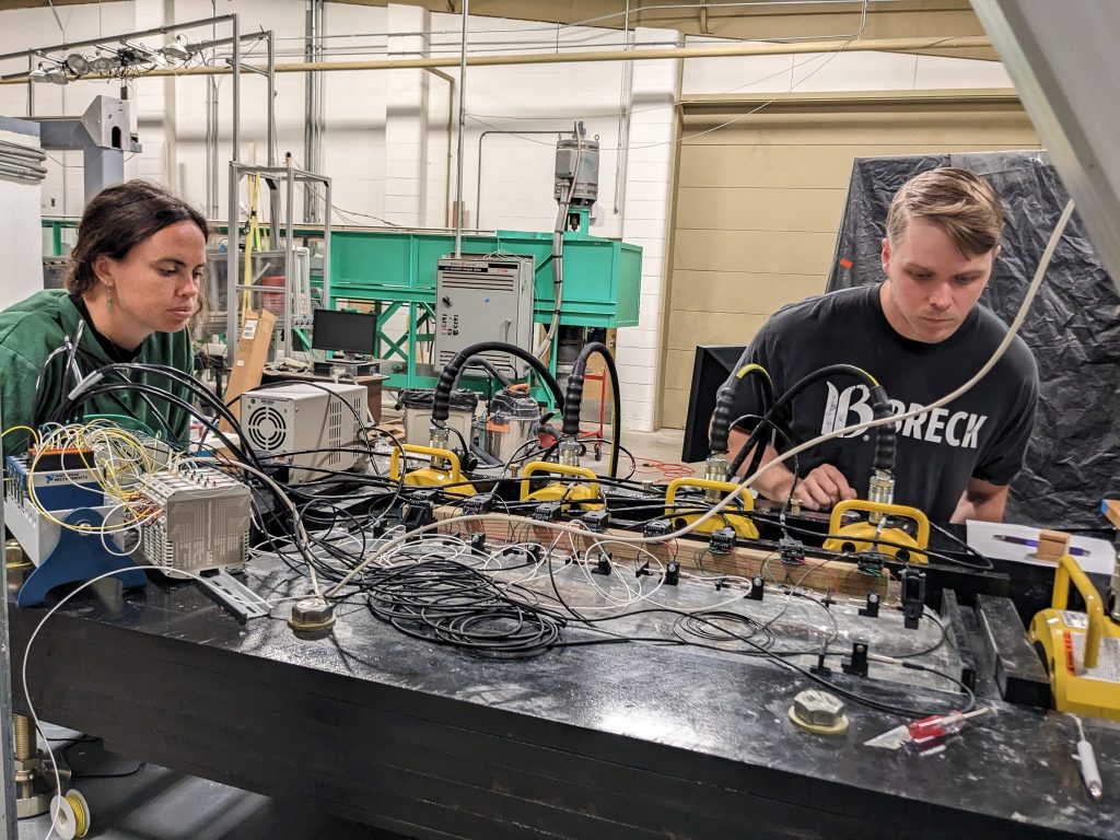 Photo of two individuals peering into a bulky instrument covered with sensors