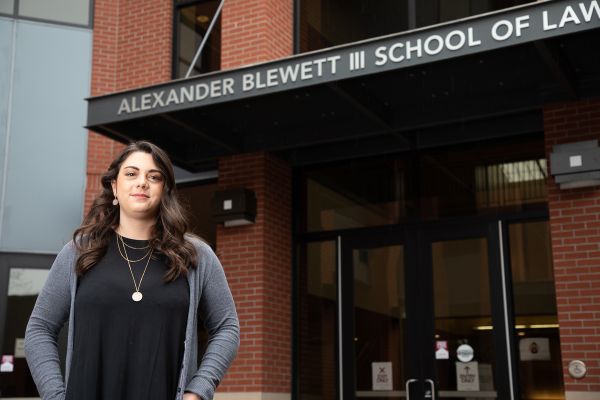 Female student stands under the School of Law entrance