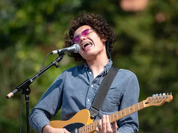 A student sings and plays guitar during an outdoor event held on UM's Oval