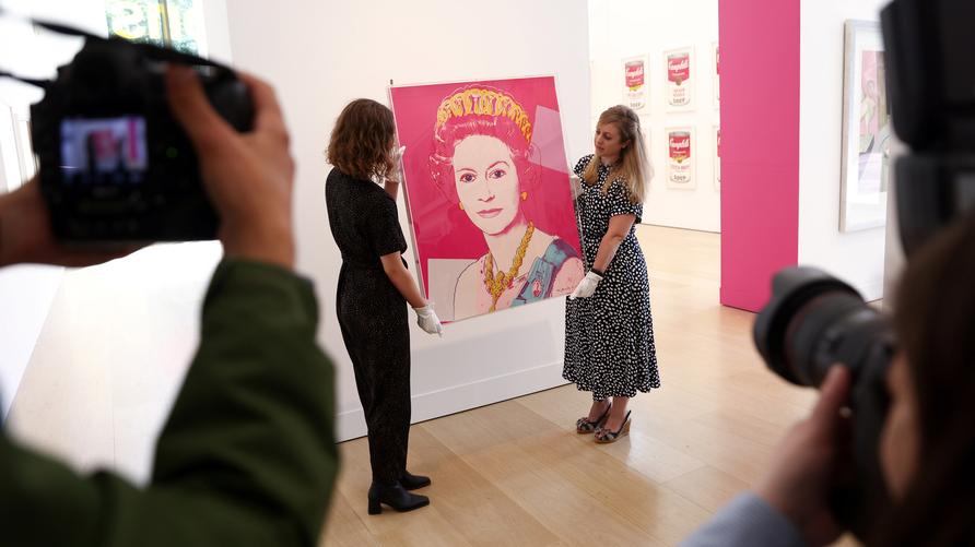 Andy Warhol: Fotografen machen Fotos, während Galerieassistenten mit „Königin Elisabeth II. des Vereinigten Königreichs, aus Reigning Queens (F. & S. 336) 1985“ von Andy Warhol posieren, bei einem Fototermin vor der Versteigerung des Kunstwerks bei Phillips in London, Großbritannien, 1. Juni 2022.