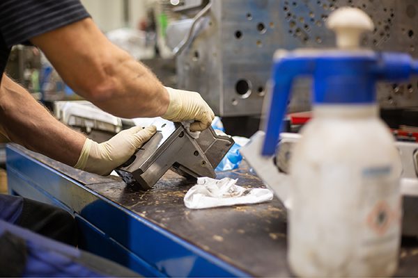 Technician cleaning metal component with solvent to remove contaminants