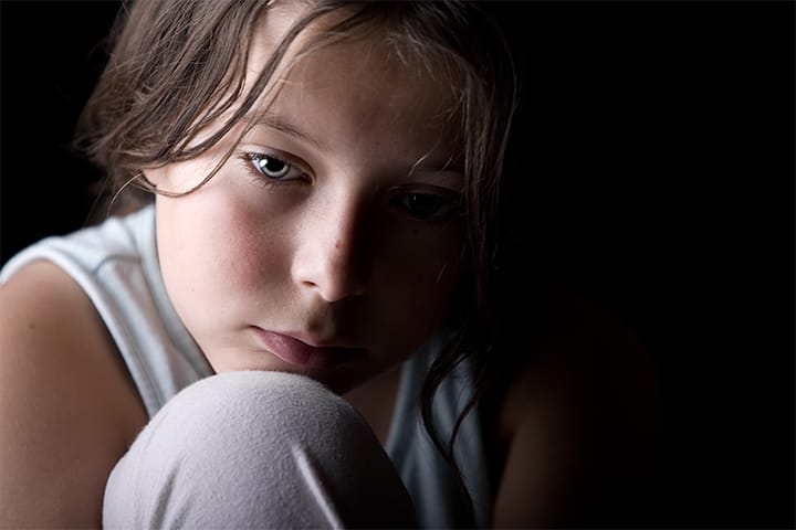 an abused child crouched down in dark corner