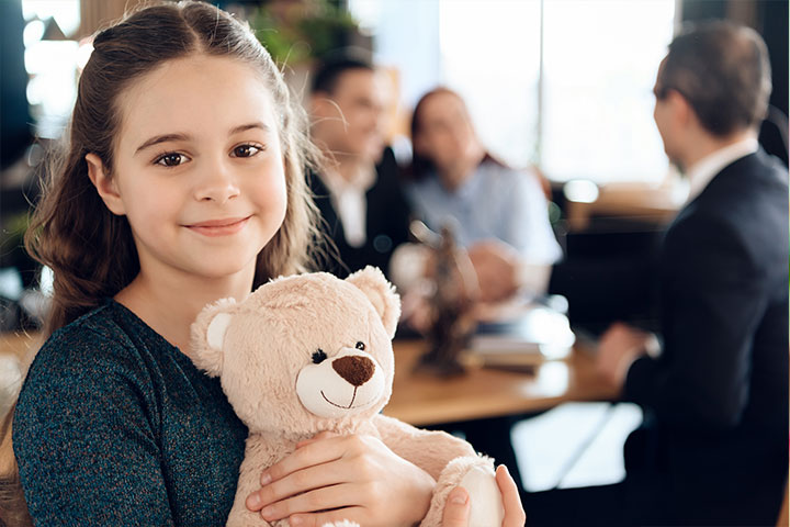 a young girl smiling holding a teddy bear