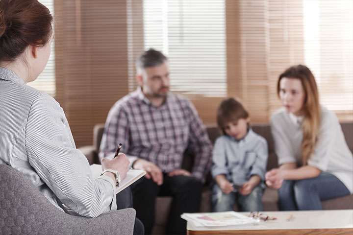 a married couple with child sitting on couch in dispair