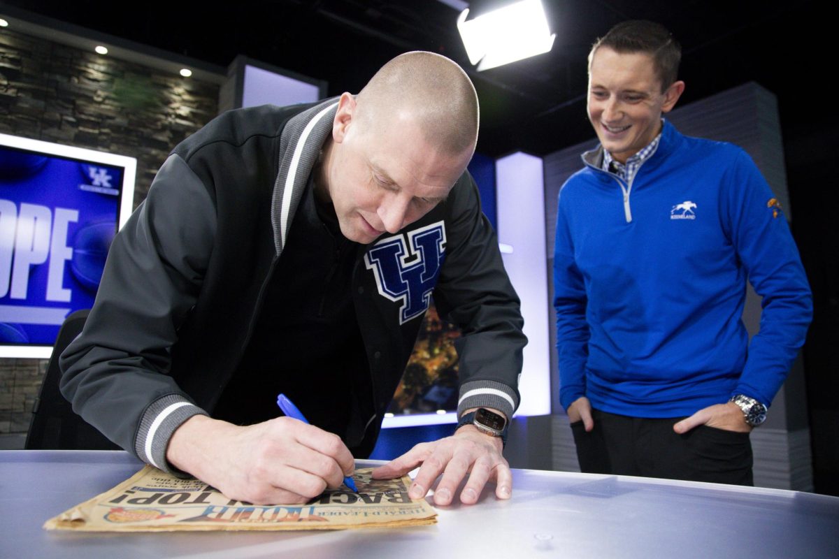 Kentucky Wildcats head coach Mark Pope signs an old newspaper for Chad Hedrick on Monday, Jan. 20, 2025, at Central Bank Center in Lexington, Kentucky. Photo by Christian Kantosky | Assistant Photo Editor