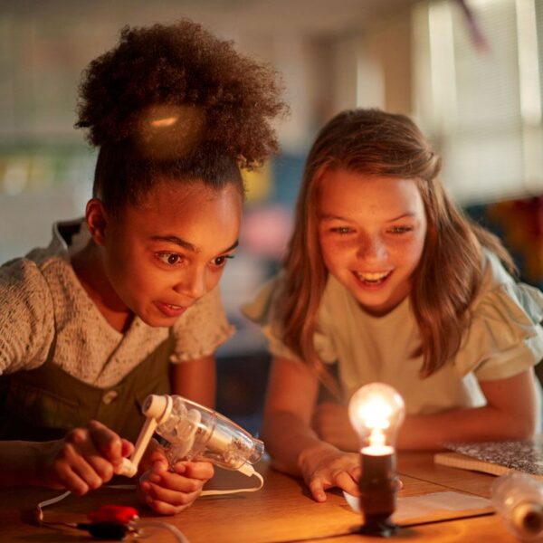 Two students light up a light bulb during a science project.