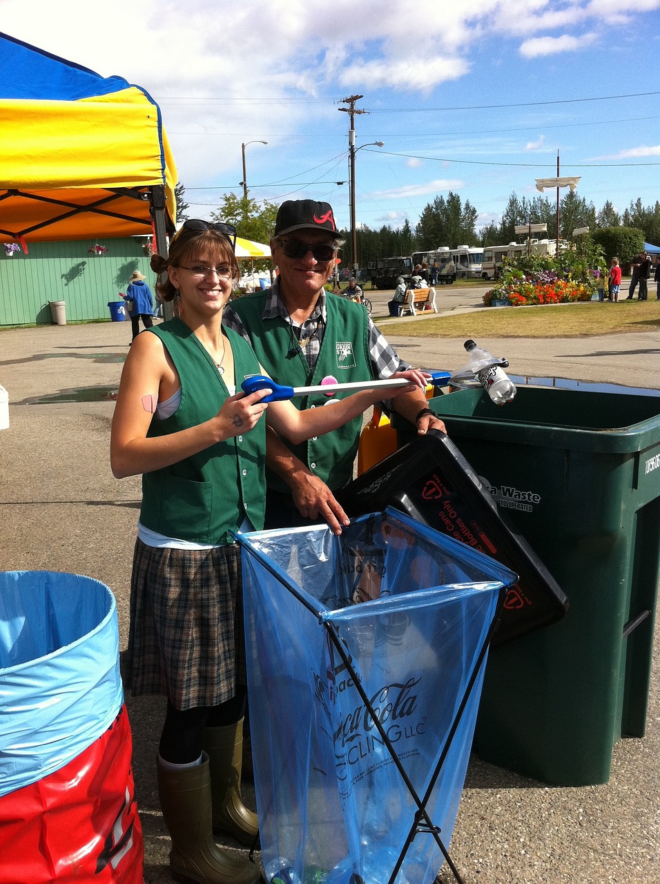 Two individuals picking up recycling in a community park.