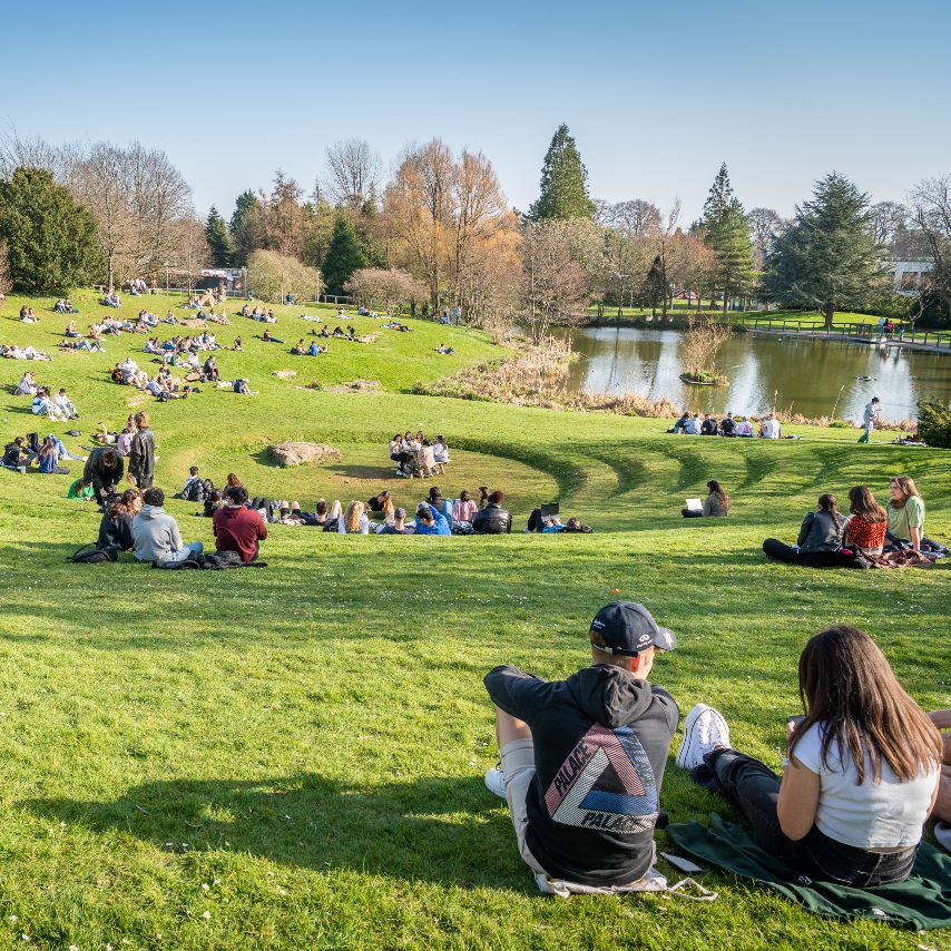 Students relaxing by the lake on campus