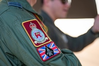 A member of the Royal Air Force speaks to a U.S. Air Force Airman during Bomber Task Force 25-1, at RAF Fairford, England, Nov. 13, 2024. The patches shown represent the 207 Squadron, which is the F-35 Lightning Operational Conversion Unit located at RAF Marham. (U.S. Air Force photo by Senior Airman Mary Bowers)