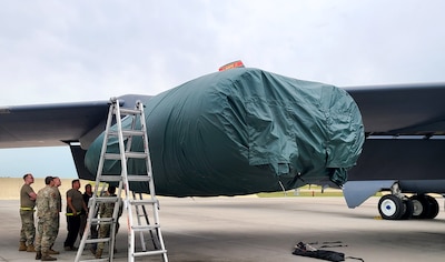 People stand around a B-52 Stratofortress that has a covered engine.