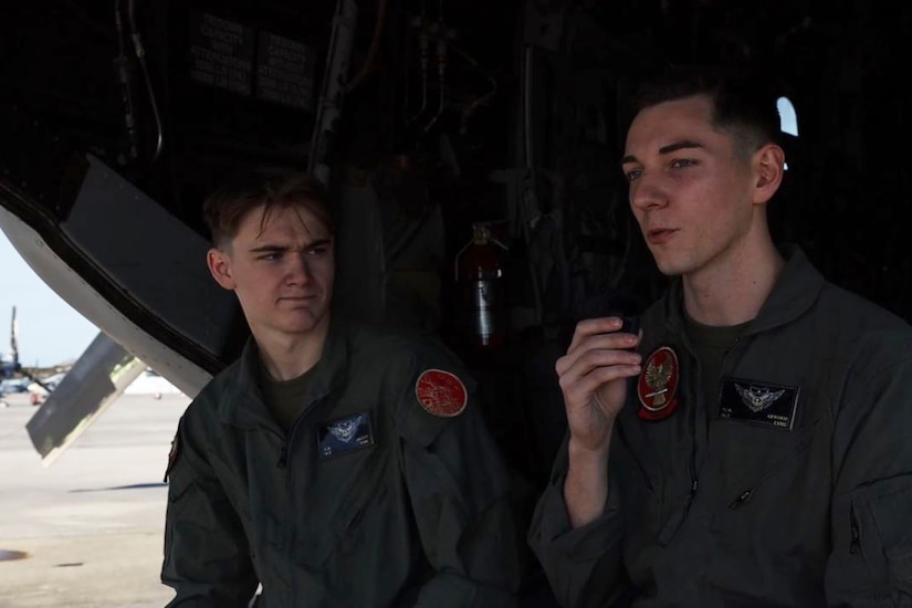 Two Marines sit in the back of an aircraft.