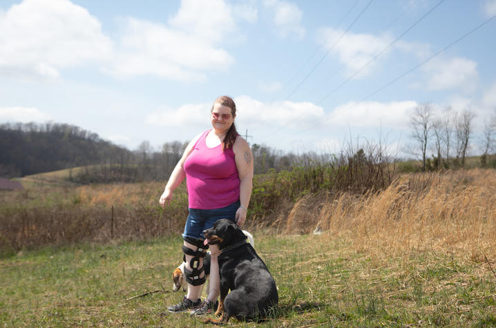 Misty Manning in a field with her dog sitting beside her.