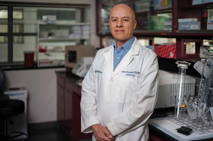 Octavio A. Gonzalez wearing a white coat, standing in a laboratory