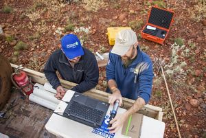 Overhead view of two TNC staff members preparing data loggers that will monitor waterhole health in Western Australia's Martu Country.