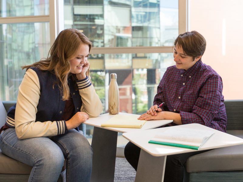 A photo of two students looking at a notebook.