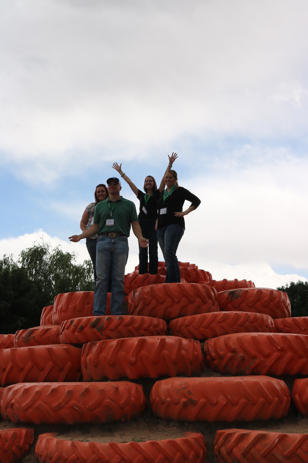 4 students standing on top of a pile of orange tractor tires.