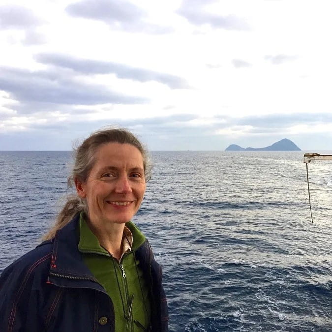 Woman smiling for a photo with the ocean behind her