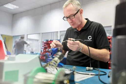 An engineer solders components for a Cryostream system, showcasing precision and focus.