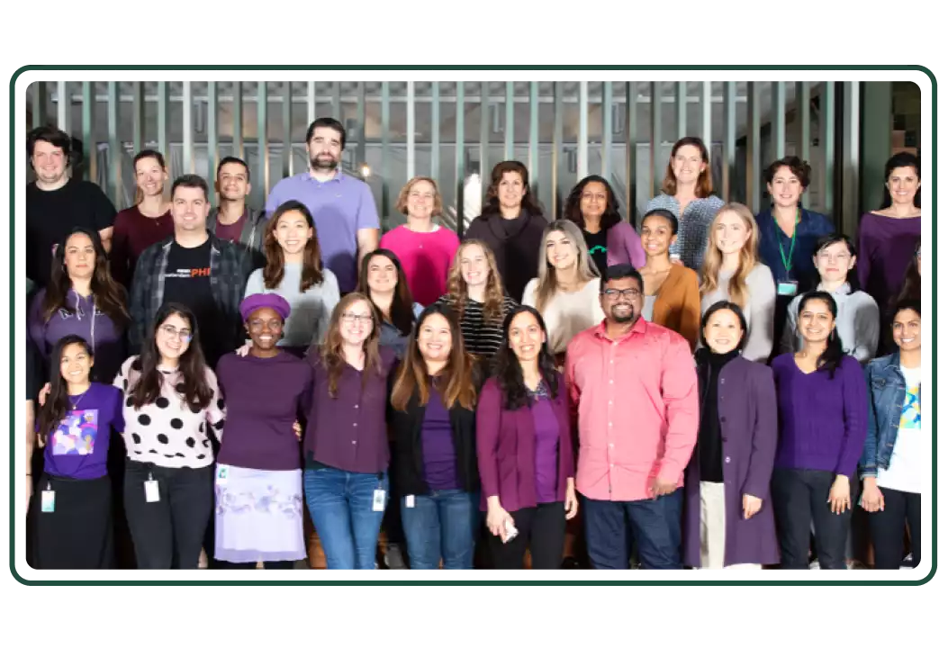 Group of employees wearing colorful shirts and posing for a group photo