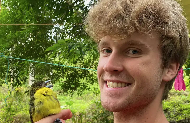 Photo of alumnus Colton Adams holding a small yellow bird