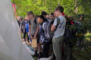 Young people gather around an insectary - a white circus-like tent that confines biocontrol insects to specific trees. 