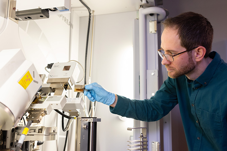 A man in glasses operates the x-ray diffraction machine at the Institute for Advanced Materials and Manufacturing.