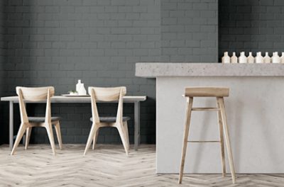 A modern kitchen with gray brick walls and concrete countertop.