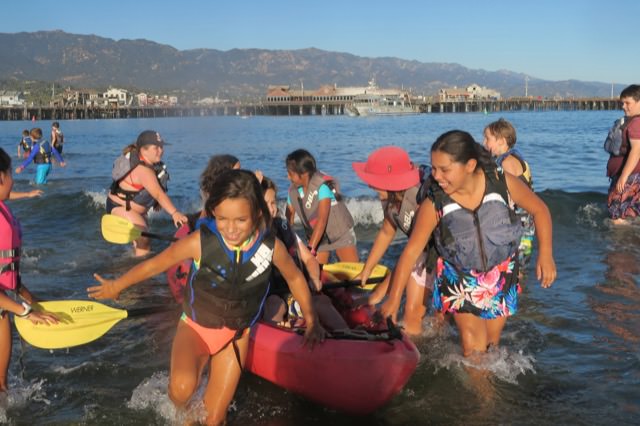 children pulling a canoe through the water