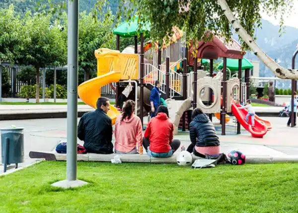 4 parents watch their kids play on a playground