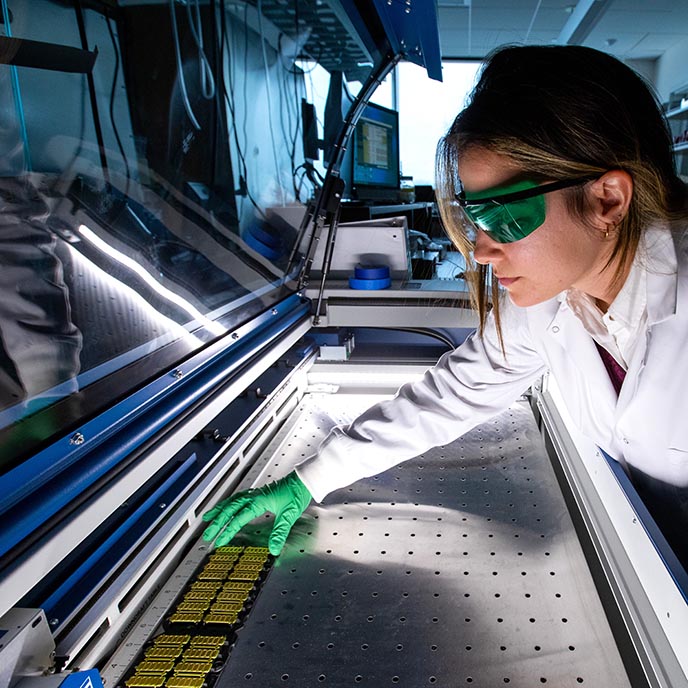 A researcher places circuit boards into lab machinery.