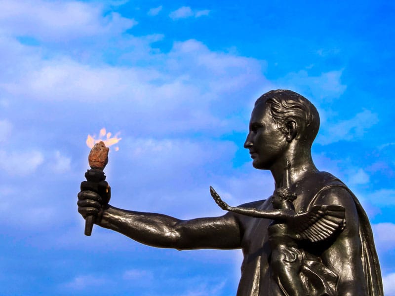 Torchbearer statue against a vivid blue sky