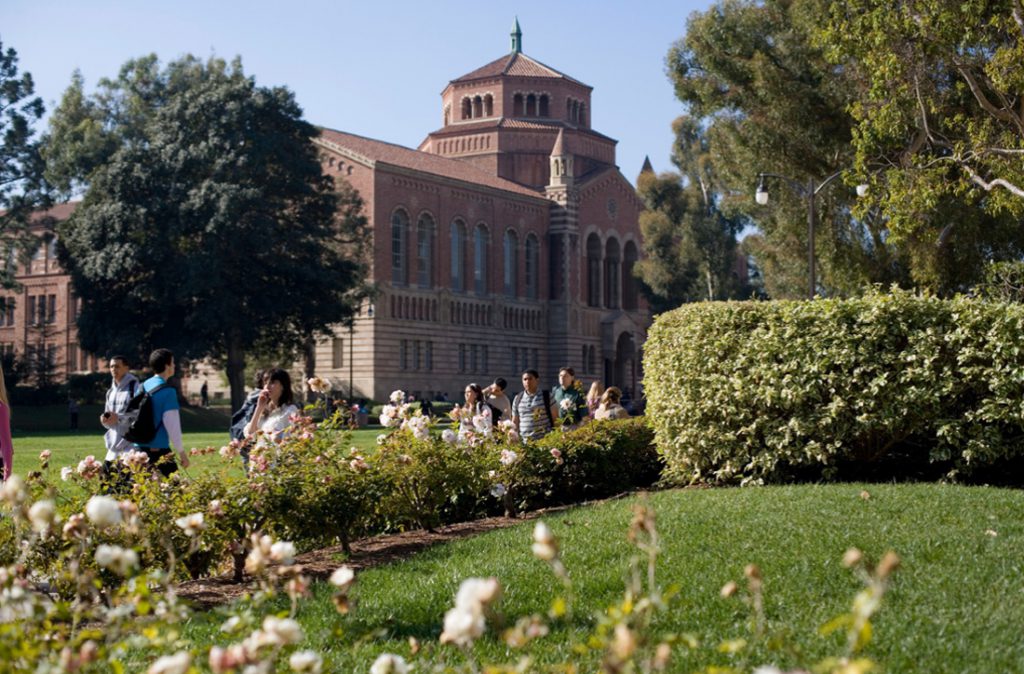 View of Powell Library from the side. Students are walking on the pathway in front of Powell Library.