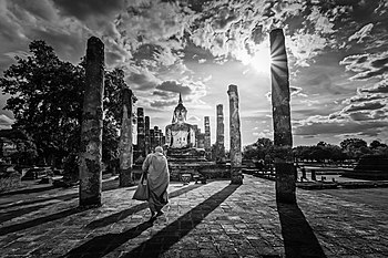 A monk walking up to the Buddha statue of Wat Maha That, Sukhothai Historical Park, Sukhothai Province Photograph: Chainfoto24 Licensing: CC-BY-SA-4.0