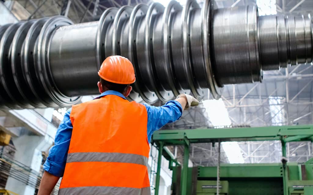 man wearing hardhat and safety vest looking at industrial equipment