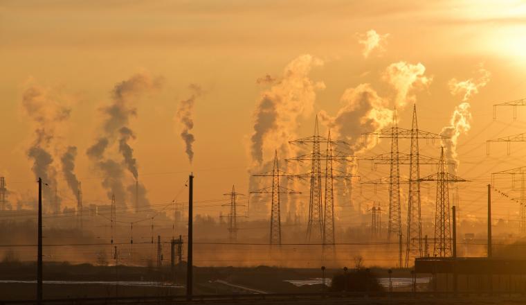 Smoke rises from a power plant at sunset.